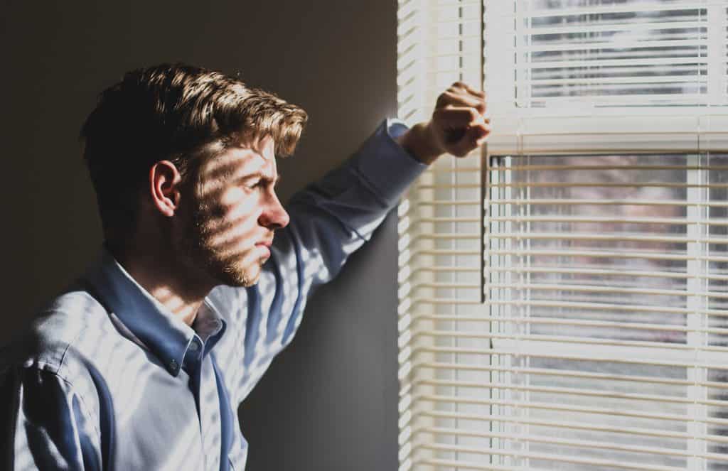 A person struggling with their mental health looking out of a window
