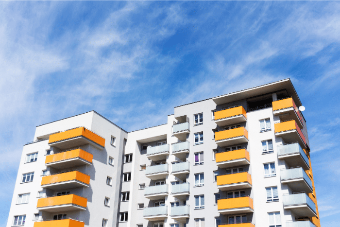 A photo of a apartment block. The walls are white and orange and there are balconies.